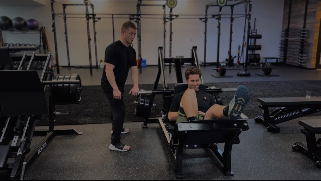 Personal Trainer with a male client using the Hack Squat