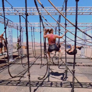 Female in her thirties completing a rope obstacle at a Tough Mudder race